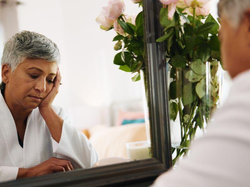 người phụ nữ soi gương và cảm thấy buồn bã, tự ti
